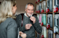 Young female shop assistant serving a senior man in a zero waste shop.